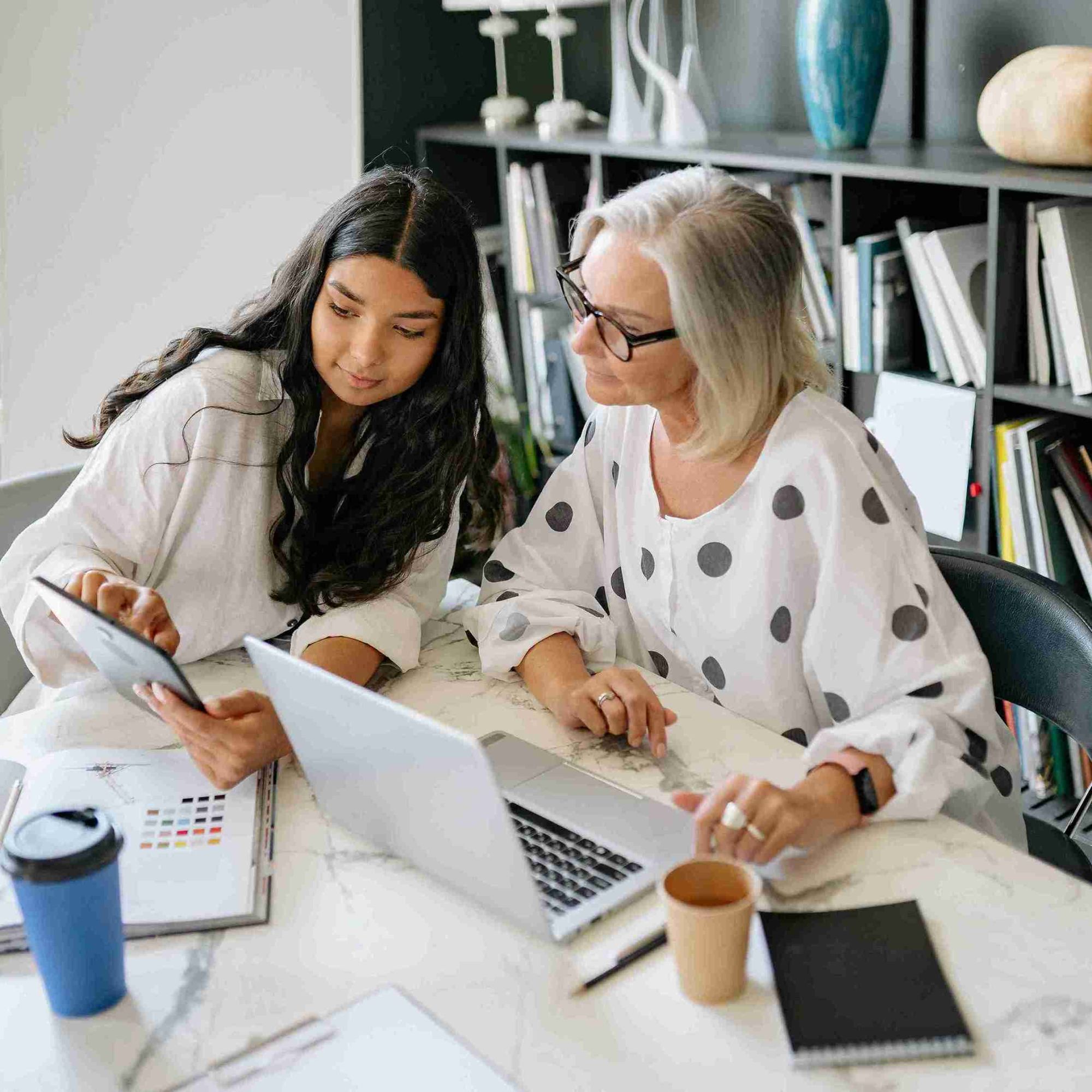 Two women engaged in conversation at a table, working together on a laptop