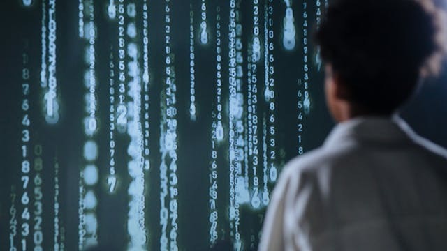 AI-Powered Assistants A person stands before a computer screen displaying streams of binary code, symbolizing digital information processing.