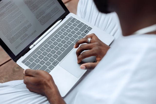 A man focused on typing on a laptop, with his hands on the keyboard and a thoughtful expression.