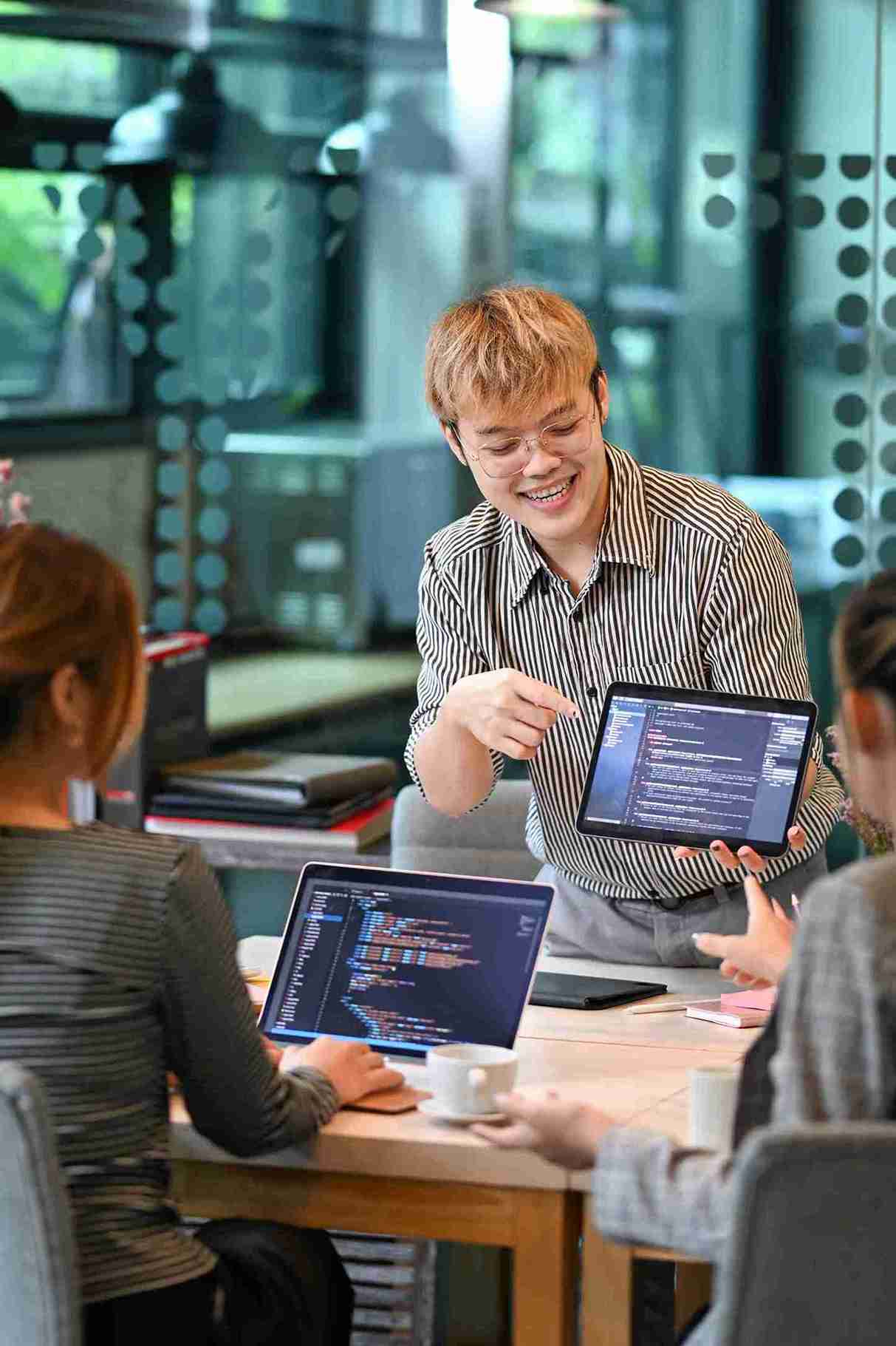 A diverse group of people collaborating around a table, each using laptops for a productive discussion.